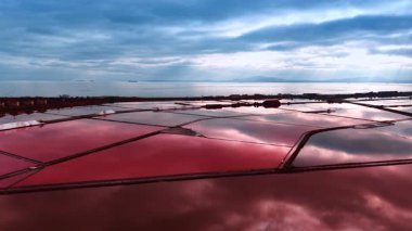 Pembe tuz göletleri dramatik bulutları yansıtır. Tuz madenciliği için çiftliklerin üzerindeki drone görüntüleri..