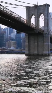 Nehir kıyısındaki Brooklyn Köprüsü 'ne yaklaşıyoruz. Tekneden New York 'un güzel simgesine alçak açıyla bakmak. Dikey video.