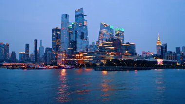 New York, ABD, 25 Ağustos 2025: Aydınlatmalı çağdaş yüksek binalı mimari. Nehirden alacakaranlıkta New York, ABD 'nin ufuk çizgisine alçak açı.