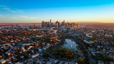 Echo Park Gölü ve Los Angeles silueti. Echo Park Gölü 'ne, palmiye ağaçlarına ve uzak şehir merkezine geniş drone bakış açısı.