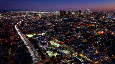 Los Angeles 'a giden gece hava yolu. Parlak bir çevre yolu farları şeridi aydınlık çekirdekten geçerek mahalleleri kesiyor..