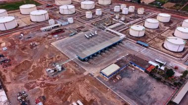 Büyük tanker kamyonlarını yakıtla doldurmak için platforma yaklaşıyoruz. Petrol depolama tankları olan büyük petrol rafineri tesisi. Hava görünümü.