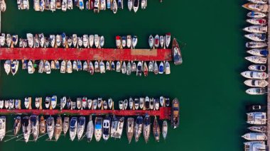Deniz yeşili deniz manzarasının her iki tarafında da gemileri olan çok sayıda rıhtım. Rıhtımda bir sürü tekneyle drone görüntüleri var..