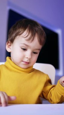 Kırmızı kalemle resim yapan bebek. Sevimli çocuk sevinçle el kaldırıyor. Kapatın. Dikey video