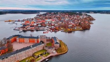 Vaxholm Adası Kalesi boyunca uçun ve yoğun şehir manzaralı başka bir adaya yaklaşın. Stockholm, İsveç kasvetli bir kış gününde.
