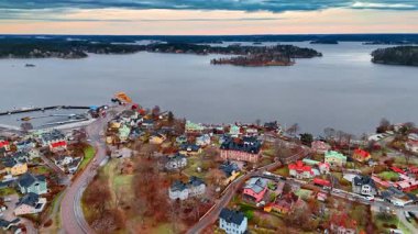 Nehir kıyısında alçak katlı evleri olan bir şehir manzarası. İsveç 'in Stockholm adalarında gri bir günde insansız hava aracı görüntüleri.