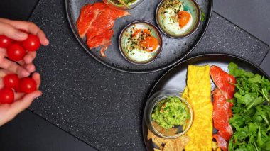 Elde tutulan kiraz domatesleri. Kahvaltı tabağının üzerinde olgun vişneli domatesleri tutan eller.