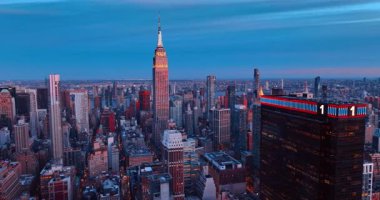 Akşam vakti Manhattan üzerinde uçuş. Empire State Binası 'nın tepesi batan güneşle aydınlanıyor. New York, ABD.
