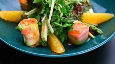 Restoranda mavi bir kasede servis edilen salata ve meyveli taze börekler. Bitki ve salatalı börekler portakal dilimli mavi bir tabakta oturur..