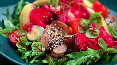 Mavi tabakta servis edilen sebzeli ve etli renkli salata. Bir salata taze sebzeler, et ve mavi tabakta süslemelerle yapılır..