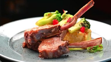 Akşam yemeği sırasında bir restoranda kuzu pirzolası ve sebze ile servis edilir. İki kuzu pirzola ve sebze bir restoranda servis edilir..