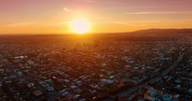 Batan güneşin altın ışığı Los Angeles, Kaliforniya, ABD manzarasını kamaştırır. Otoyollar gün batımında hareket halindeki bir sürü arabayla dolu..