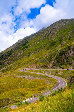 Kayalık yamaçta virajlı dağ yolu. Keskin asfalt eğrisi Karpatlar 'da kayalık yeşil dağ yamacını takip eder