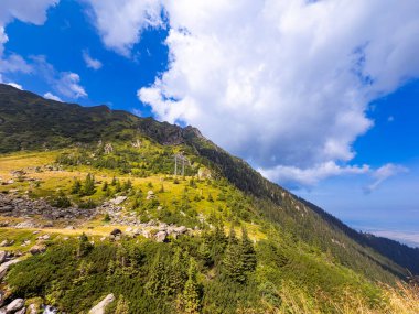 Güneşli dağ yamacı bulutların altında. Orman ve bulutların altındaki kayalık arazisiyle Karpat Dağları