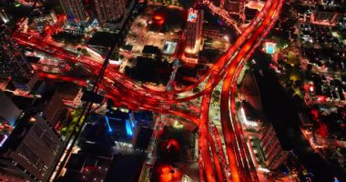 Miami, ABD, 4 Ağustos 2025: Çok sayıda araba çok katlı otobanlardan ve kırmızı ışıkla aydınlatılmış merdivenlerden geçiyor. Miami, Florida, ABD 'de gece trafik sıkışık. Hava görünümü.