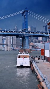 New York, ABD, 25 Ağustos 2025: Manhattan Köprüsü ve feribot East River 'da. Manhattan Köprüsü 'nün altına yanaşan feribot East River' da aşağı Manhattan silueti var..