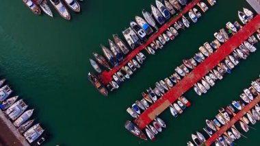 Birden fazla teknesi olan huzur dolu deniz yeşili bir su manzarası. Limandaki rıhtımlarda çeşitli tekneler var..