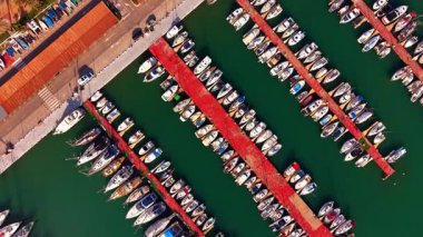 Deniz yeşili sudaki rıhtımlar birden fazla gemiyle çevrili. Limanda tekneler ve yatlar var. İnsansız hava aracı görüntüleri.