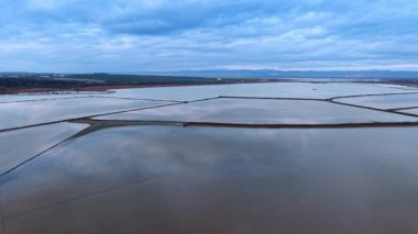 Tuz buharlaştırma tavalarının geometrik düzeni bulutlu gökyüzü altında. Tuz kristalizasyonu için ince barajlarla ayrılmış endüstriyel su birikintilerinin simetrik görüntüsü.