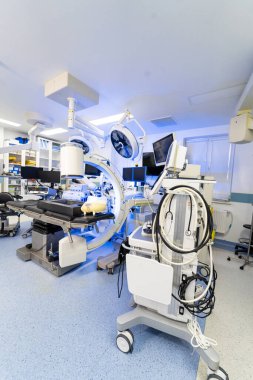 Mobil anestezi çalışma istasyonu ve ameliyat odasındaki izleme sistemi. Yüksek teknolojili bir ameliyat ortamında cerrahi masasının yanında tüplü, monitörlü ve teşhis cihazlı tıbbi araç görüntüsü..