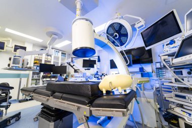Robotik röntgen sistemi olan yüksek teknolojili hibrit işletim odası. C-kolu floroskopi makinesi ve tıbbi monitörlü modern cerrahi süitin içi..