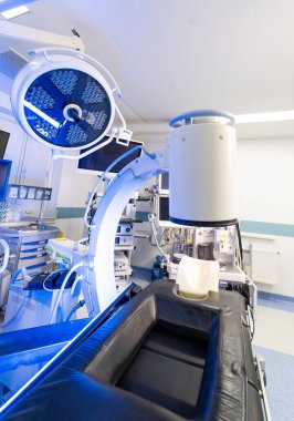 C-kolu ile geniş açılı melez ameliyathane. Gelişmiş görüntüleme ekipmanları ve mavi çevre ışıklandırmasına sahip modern cerrahi tesisi.