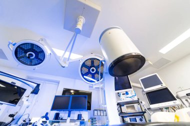 Ameliyat ışıkları ve görüntüleme ekipmanları hastane süitinde. Modern bir klinikte çift cerrahi lambaların ve C-kol sisteminin genel görünümü.