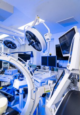 C-kolu ve monitörleri olan yüksek teknoloji beyin cerrahisi odası. Floroskopi C-kolu, yukarıdaki ışıklar ve izleme istasyonu da dahil olmak üzere cerrahi süitin geniş görüşü..