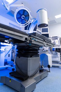 Cerrahi ışık ve monitörlerle modern nöroşirürji masası. Yüksek teknolojili bir ameliyathanede ayarlanabilir bir cerrahi yatağın düşük açılı görüntüsü..