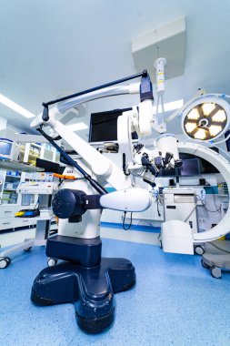 Yüksek teknoloji cerrahi mikroskop ve beyin cerrahisinde C kolu. Görüntüleme monitörleri ve hastane ekipmanlarıyla çevrili ağır bir üste cerrahi mikroskop..