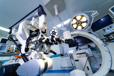 Ameliyathanedeki robotik nörocerrahi mikroskobun detaylı görüntüsü. Çift göz kapakları ve entegre ışıklandırma ile karmaşık bir cerrahi mikroskop düşük açılı perspektif.