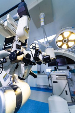 Ameliyathanede robotik cerrahi mikroskop dikey görüntüsü. Dikey bileşim, arka planda cerrahi ışıkları olan nörocerrahi bir mikroskop gösteriyor..