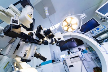 Profesyonel nöroşirürji mikroskobu. Cerrahi süitte kontrol kolları var. Steril bir odada parlak LED ışıkları altında cerrahi mikroskobun geniş açı perspektifi.