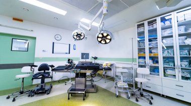 Boş modern beyin cerrahisi ameliyathanesi. Masası ve ekipmanı var. Ayarlanabilir masa, ışık ve dolapların yer aldığı geniş bir cerrahi tiyatro manzarası.