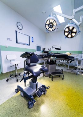 Tıbbi ışıklandırması ve masası olan profesyonel cerrahi odası. Ameliyat masası, tıbbi tabure ve LED lambalı steril ameliyathane manzarası.