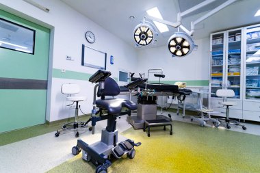 Ameliyat masası ve ışıklandırma ekipmanlarıyla modern boş ameliyathane. Gelişmiş ameliyat masası ve LED ışıkları olan steril bir tıp tiyatrosu..