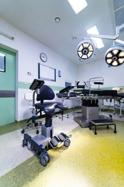 Steril odada özel ameliyat koltuğu ve ameliyat masası. Parlak bir ameliyathanenin önünde profesyonel ergonomik cerrah koltuğu..