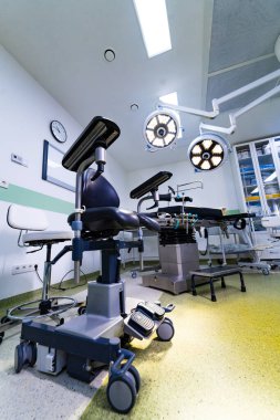 Ergonomik cerrah koltuğu ve ameliyathanede cerrahi ışıklar. Steril cerrahi bölümünde tıbbi mobilya ve ışıklandırma düşük açılı görünüm.