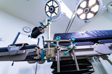 Ameliyat masasının ve ameliyat ışıklarının altında. Tiyatroda tıbbi ekipman ve tepedeki lambaların teknik perspektifi.