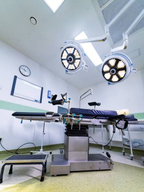 Steril ortamda modern çalışma masasına tam bir bakış açısı. Parlak bir klinikte bacak destekli ayarlanabilir bir ameliyat masasının profili.