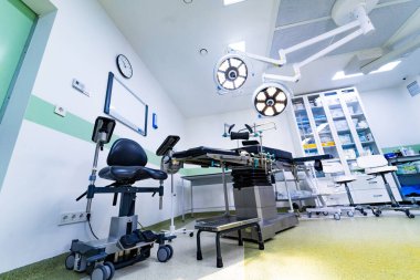 Masa lambaları ve sandalyeli ameliyathane manzaralı. Ameliyat yatağı, ışıklandırma ve tıbbi mobilyaları olan kapsamlı bir klinik ameliyathane..