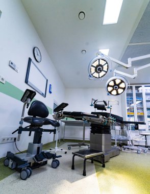Ameliyat masası ve ayarlanabilir LED ışıkları olan modern ameliyathane. Steril bir tıbbi tiyatronun içinde cerrahi ekipman, cerrah koltuğu ve parlak tavan ışıklandırması..
