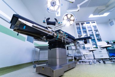 Tıbbi ameliyat masası ve lambaların düşük açılı görüntüsü. Modern bir klinikte parlak başlıklı lambaların altında steril bir ameliyat masası görüntüsü..