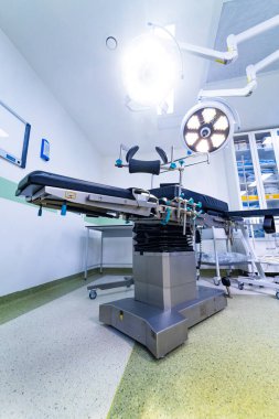 Steril odada ameliyat masasının üzerinde parlak cerrahi lambalar. Modern bir tıp tiyatrosunu aydınlatan profesyonel ameliyat ışıklarının üst perspektifi.