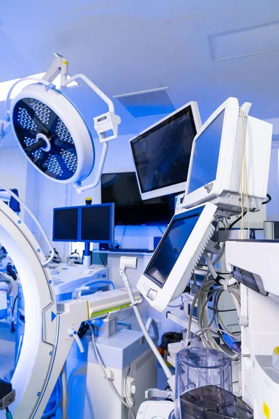 Nöroşirürji odasının, monitörlü ve cerrahi lambalı kapsamlı görüntüsü. Tıbbi monitörlerin, ameliyat ışıklarının ve karmaşık ekipmanların bulunduğu modern bir ameliyathane geniş açıdan görülüyor..
