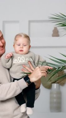 Mutlu baba oğluna evde yetişen bitkiyi gösteriyor. Küçük çocuk ağaca şaşkınlıkla bakıyor. Dikey video