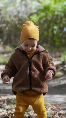 Sonbaharda doğada yürüyen tuhaf beyaz bir çocuk. Küçük oğlan aşağı bakıyor. Dikey video