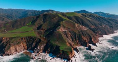 Big Sur 'daki sarp kayalıkların ve 1. Otoyol' un havadan görüntüsü. Kıyıdaki otobanın yüksek açılı görüntüsü okyanus dalgalarının üzerinde bir uçurum kenarına tünemiş..