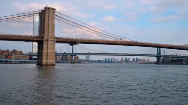 Brooklyn Köprüsü ve Manhattan Köprüsü kasvetli bulutlu bir günde. Nehirden New York 'un ünlü simgelerine alçak açılı bir bakış açısı.