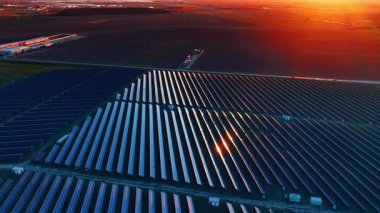 Devasa güneş panelleri dosyasındaki görüntüler. Gün batımının parlak turuncu ışığı manzarayı renklendirir..